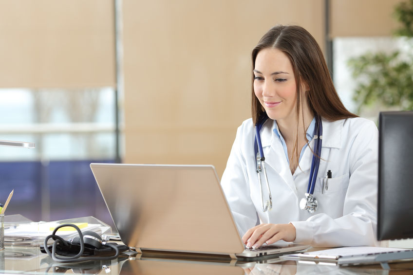 A nurse checks out a computer chart at her desk.